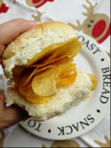 Hand holding white roll containing crisps, festive setting