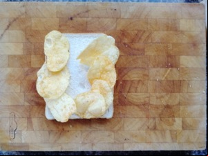 Seven crisps on white bread on a chopping board