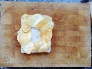 Eight crisps on white bread on a chopping board
