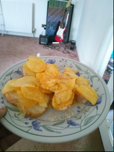 Crisps on white bread approaching a guitar