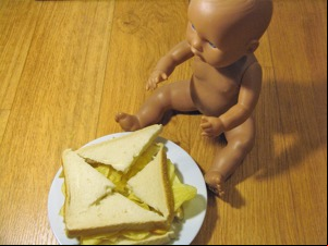 Quartered crisp sandwich alongside a doll