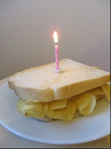 A birthday candle on a white crisp sandwich