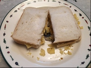 Sliced white bread containing crisps and cut in half